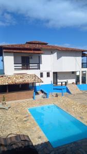 a villa with a swimming pool in front of a house at Pousada MARIA BONITA in Rio das Ostras