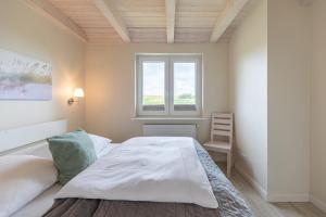 a bedroom with a large white bed and a window at Marie in Dagebüll