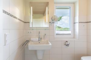 a white bathroom with a sink and a window at Marie in Dagebüll