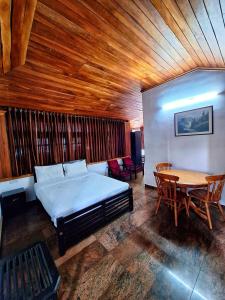 a bedroom with a bed and a wooden ceiling at Casalinda munnar by Foxinroom in Devikolam