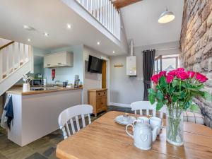 cocina y comedor con mesa de madera con flores rosas en Jacob's Barn - Uk46733, en Wootton