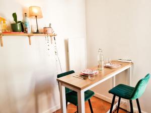 a dining room table with two green chairs and a table with glasses at EXIGEHOME-Large studio with terrace 15 min Paris-La Défense in Suresnes