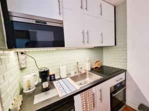 a kitchen with white cabinets and a sink at EXIGEHOME-Large studio with terrace 15 min Paris-La Défense in Suresnes +20 photos