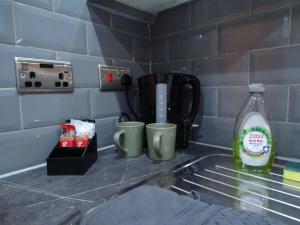 a kitchen counter with two cups and a bottle of milk at The Orange Outpost 8a - City Centre in Bradford