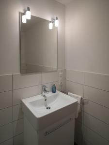 a white bathroom with a sink and a mirror at Hotel Inselfriede in Spiekeroog
