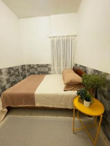 - une chambre avec un lit et une table jaune dans l'établissement TheMerits Homestay, à Ipoh 1 autre photo