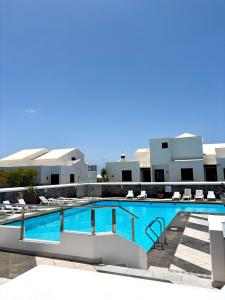 a large swimming pool with chairs and a building at La Necora Lanzarote in Playa Honda +15 photos