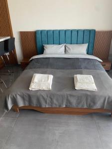 a bed with a blue headboard and two towels at Iskele Courtyard Long Beach Apartment in Iskele +36 photos
