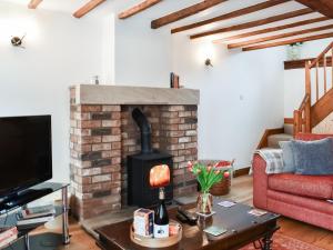 a living room with a brick fireplace and a red couch at Summerville Cottage in Kirkby Stephen