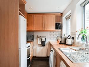 a kitchen with wooden cabinets and a white refrigerator at Summerville Cottage in Kirkby Stephen