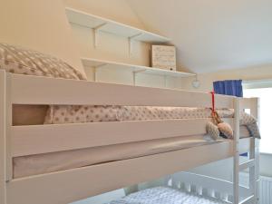 a bedroom with a bunk bed with shelves at Sweet Pea Cottage in Heacham