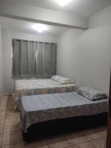 two twin beds in a room with a window at Apartamento bem localizado para até 4 hóspedes in Brasilia +3 photos