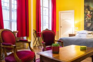 a room with a bed and chairs and a table at Appartement Le Buffon in Dijon