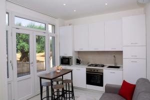 a kitchen with white cabinets and a table and chairs at Perla D'Itria in Locorotondo