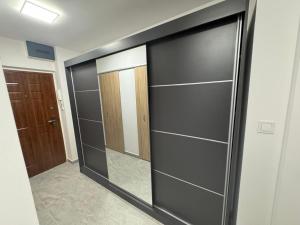 a walk in closet with black doors and a mirror at Zora Apartman in Veszprém