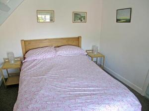 a bedroom with a bed with a purple blanket at Honeysuckle Cottage - 23227 in Embleton
