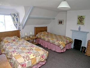 a hotel room with two beds and a fireplace at Honeysuckle Cottage - 23227 in Embleton