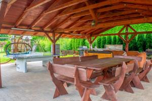 a large wooden table and chairs under a pavilion with a ping pong table at Penzion K in Rudník