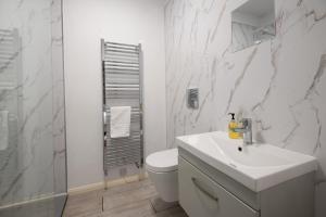 a white bathroom with a toilet and a sink at Northumberland Hot Tub Haven for 10 in 5 ensuite bedrooms in Chatton +22 photos