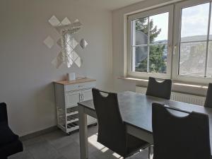 a dining room with a table and chairs and two windows at Lier Stays in Meschede