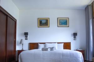 Real Hotel Huascaran في هواراس: غرفة نوم بسرير ابيض مع وجود صورتين على الحائط