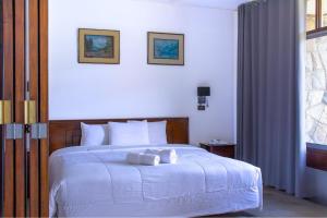 Real Hotel Huascaran في هواراس: غرفة نوم بسرير ابيض عليها منشفتين