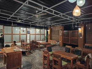 a dining room with wooden tables and wooden chairs at Moondance Hostel & Garden Restaurant in Pushkar