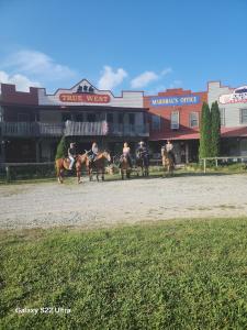 a group of people riding horses on a race track at True West Campground in Jamestown