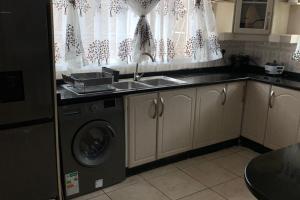 a kitchen with a sink and a washing machine at 4 Bed Gated House-Sleeps 8-Private Parking in Harare +11 photos