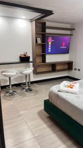 a room with a bed and two stools and a tv at Apartaestudio moderno en el centro de la ciudad in Manizales