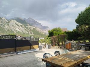 a wooden table and chairs with mountains in the background at Appartement avec terrasse au pied des cols et des stations de ski in Villargondran