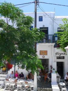 a group of people sitting at tables in front of a building at Glitterati Corner in Mikonos