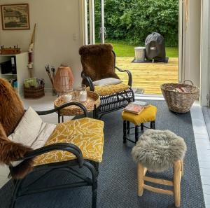 a living room with chairs and tables and a patio at Holiday Home With Charming Interior On Langeland in Tranekær