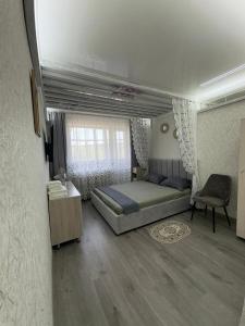 Un dormitorio con una cama y una silla y una ventana. en Кривенко 85, en Pavlodar