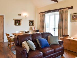 a living room with a leather couch and a table at High Dalton Hall Cottage in Newsham