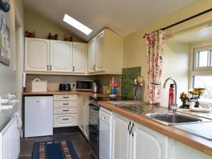 a kitchen with white cabinets and a sink at High Dalton Hall Cottage in Newsham