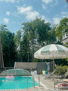 a swimming pool with an umbrella and a table and chairs at Charming 1900S Cottage In Billinge Village in Norrtälje