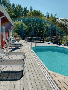 a swimming pool on a wooden deck with chairs and umbrellas at Charming 1900S Cottage In Billinge Village in Norrtälje