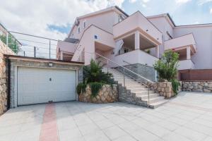 a large pink house with a garage and stairs at Apartments in Klimno - Insel Krk 13574 in Klimno