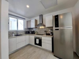 プンタ・カナにあるComfortable 1BDR in Cana Pearl with Lake/Golf Viewの白いキャビネットとステンレス製の冷蔵庫を備えたキッチン
