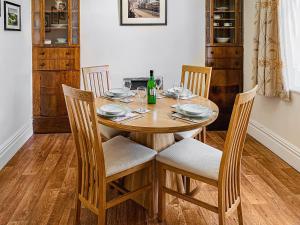 una mesa de madera con sillas y una botella de vino en Isallt, en Nantlle