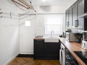 a kitchen with black and white cabinets and a sink at Prospect Cottage in Catton
