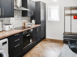 a kitchen with black cabinets and white appliances at Prospect Cottage in Catton