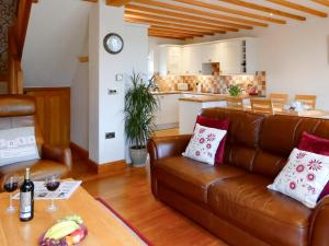 a living room with a brown leather couch and a kitchen at Wold View Cottage in Rillington