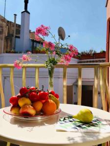 a plate of fruit on a table with a vase of flowers at Accommodates 5 people between Ibla and Ragusa in Ragusa