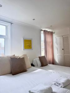 a bedroom with a large white bed with a window at BoHo BreeZe Rooms in Brighton & Hove
