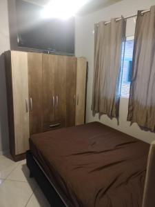 a bedroom with a bed and wooden cabinets and a window at Recanto da vila in Garopaba