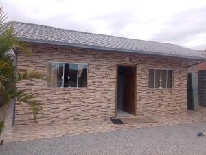 a house with a brick wall and a window at Recanto da vila in Garopaba