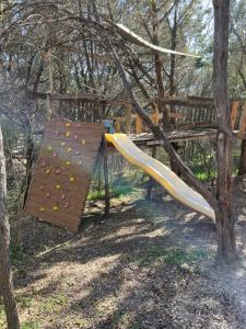 a playground with a slide and a tree at The Studio at Creekside Camp & Cabins in Marble Falls