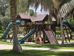 a playground with a slide in a park with palm trees at Hawana VIP Appartment in Ma‘mūrah